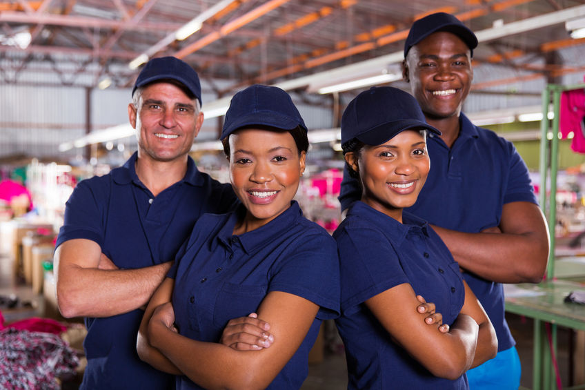 four staff members of a manufacturing company standing with their arms crossed
